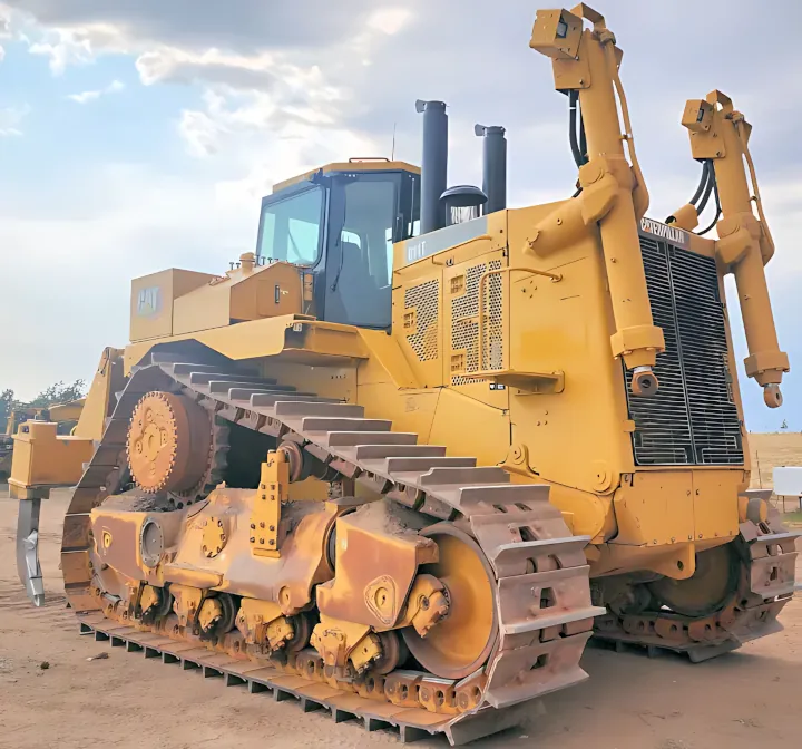 A massive yellow bulldozer featuring oversized tracks and an elevated operator cab, positioned on a dirt lot.