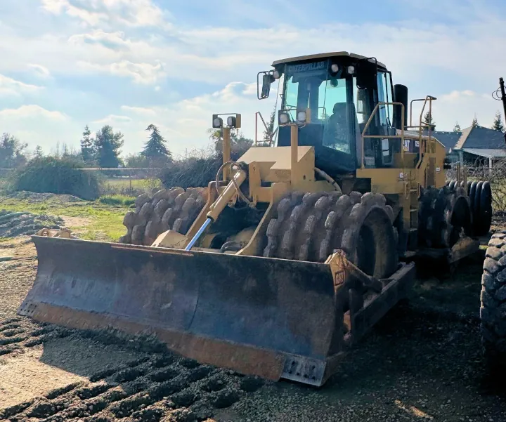 A powerful 2014 Caterpillar 825H soil compactor, engineered for compaction and dozing, is parked in a dirt lot.