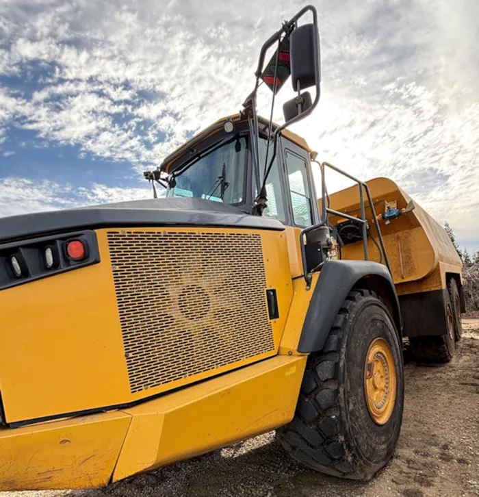 A detailed view of a yellow 2015 John Deere 410E water truck parked on a dirt lot.