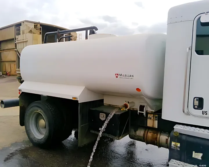 A large white 2019 Kenworth T270 water truck, featuring a massive water cylinder, is releasing water onto a concrete surface.
