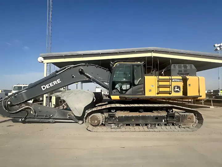 A large yellow 2022 Deere 470 GLC excavator is parked on a concrete lot, with its arm folded inward and the machine at rest.