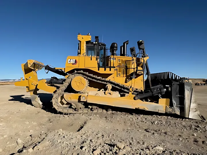A side profile of a large yellow 2024 Cat D10 bulldozer featuring a black front blade, positioned on a dirt lot.